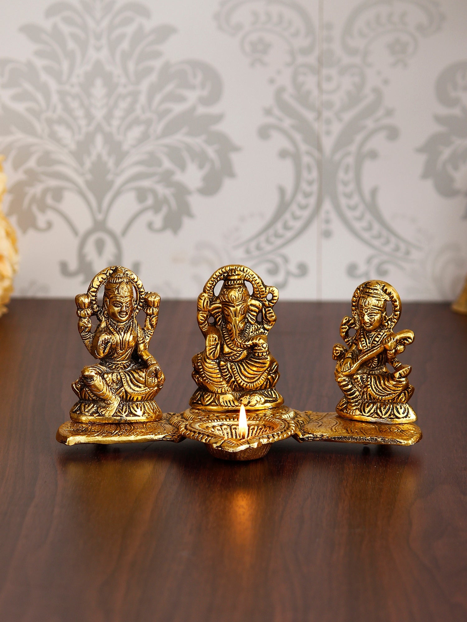 Gold Metal Handcrafted Laxmi Ganesha Saraswati Idols with Diya on Leaf Chowki Kafalo