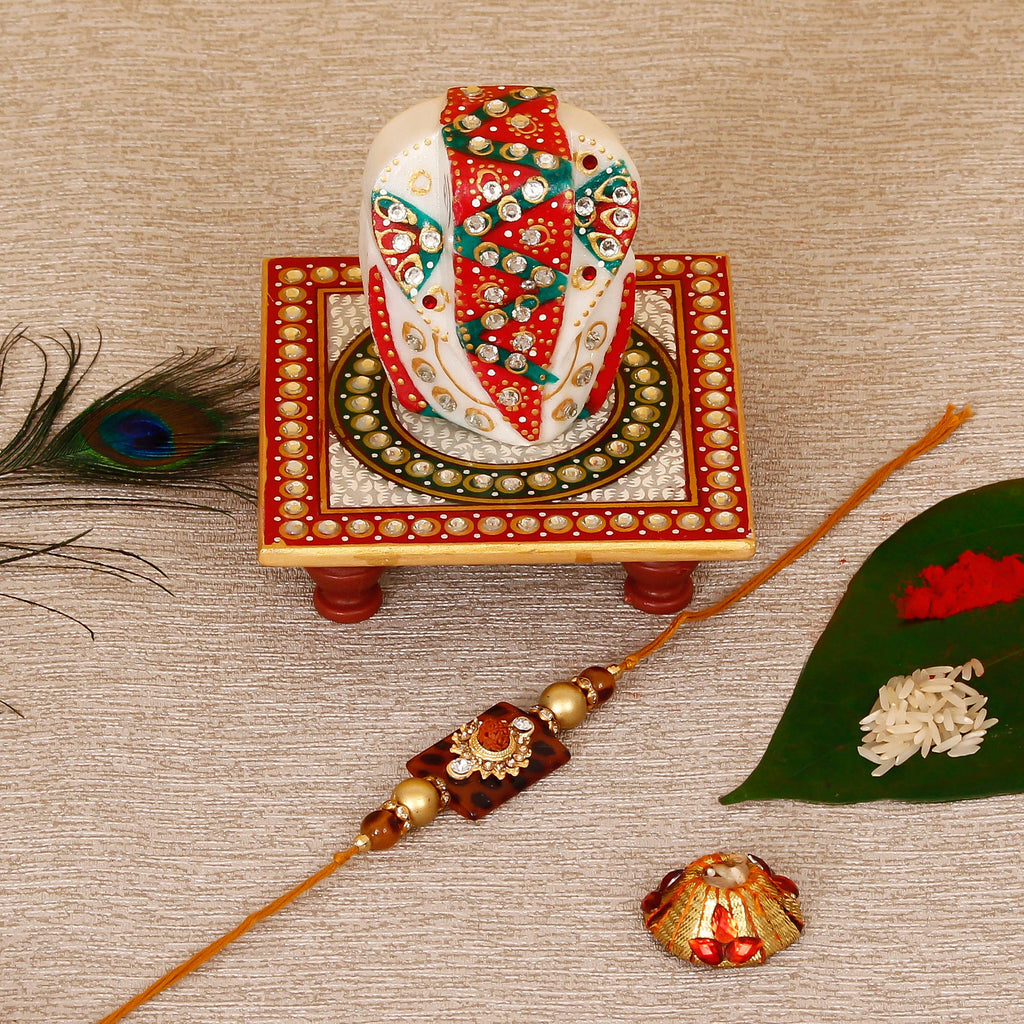 Stone Rudraksh Rakhi with Lord Ganesha on Kundan Studded Marble Chowki and Roli Tikka Matki Kafalo