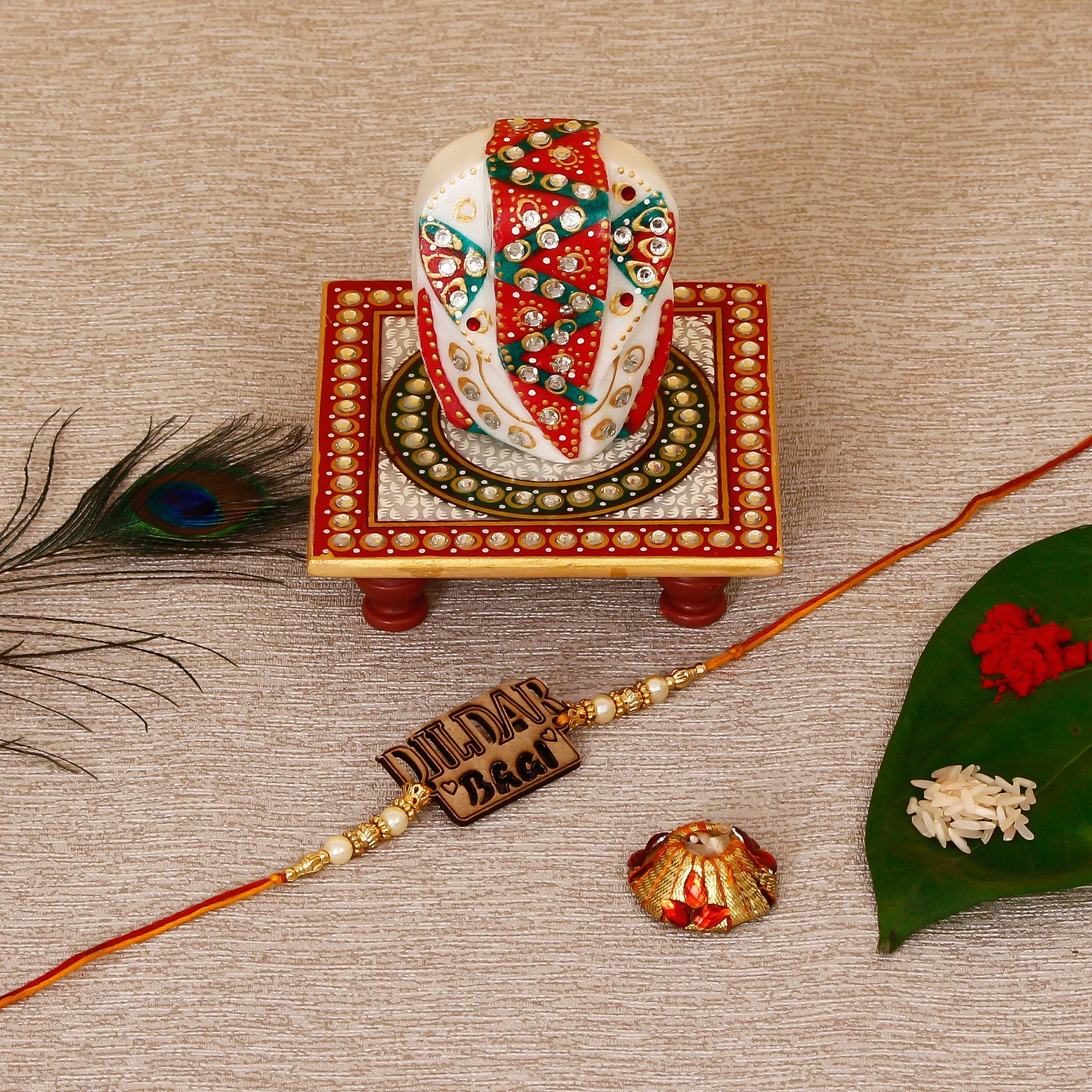 Designer Wooden Dildar Bhai Rakhi with Lord Ganesha on Kundan Studded Marble Chowki and Roli Tikka Matki Kafalo