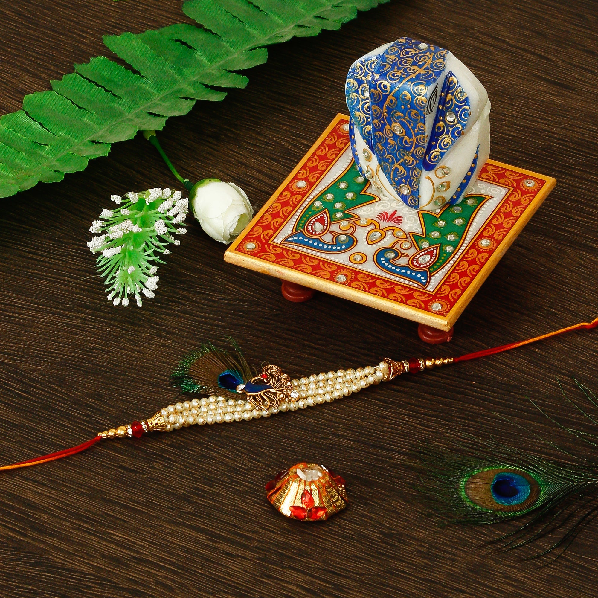 Designer Pearl Morpankh Rakhi with Lord Ganesha on Marble Chowki and Roli Tikka Matki Kafalo
