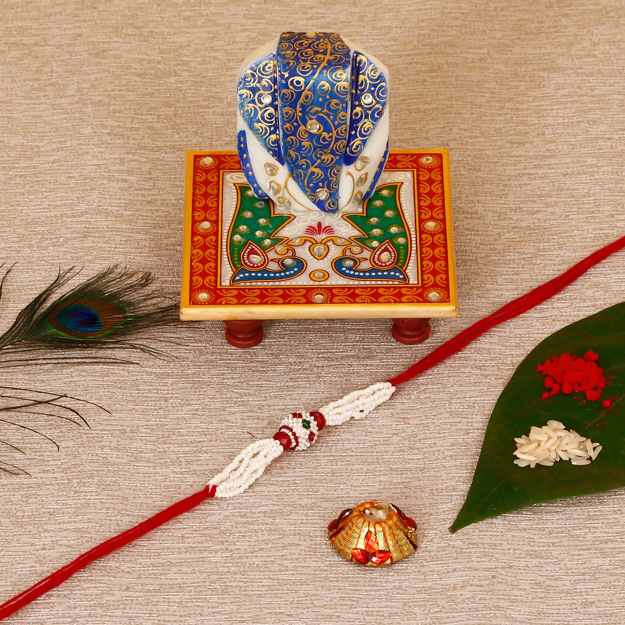 Designer Pearl Rakhi with Lord Ganesha on Marble Chowki and Roli Tikka Matki Kafalo