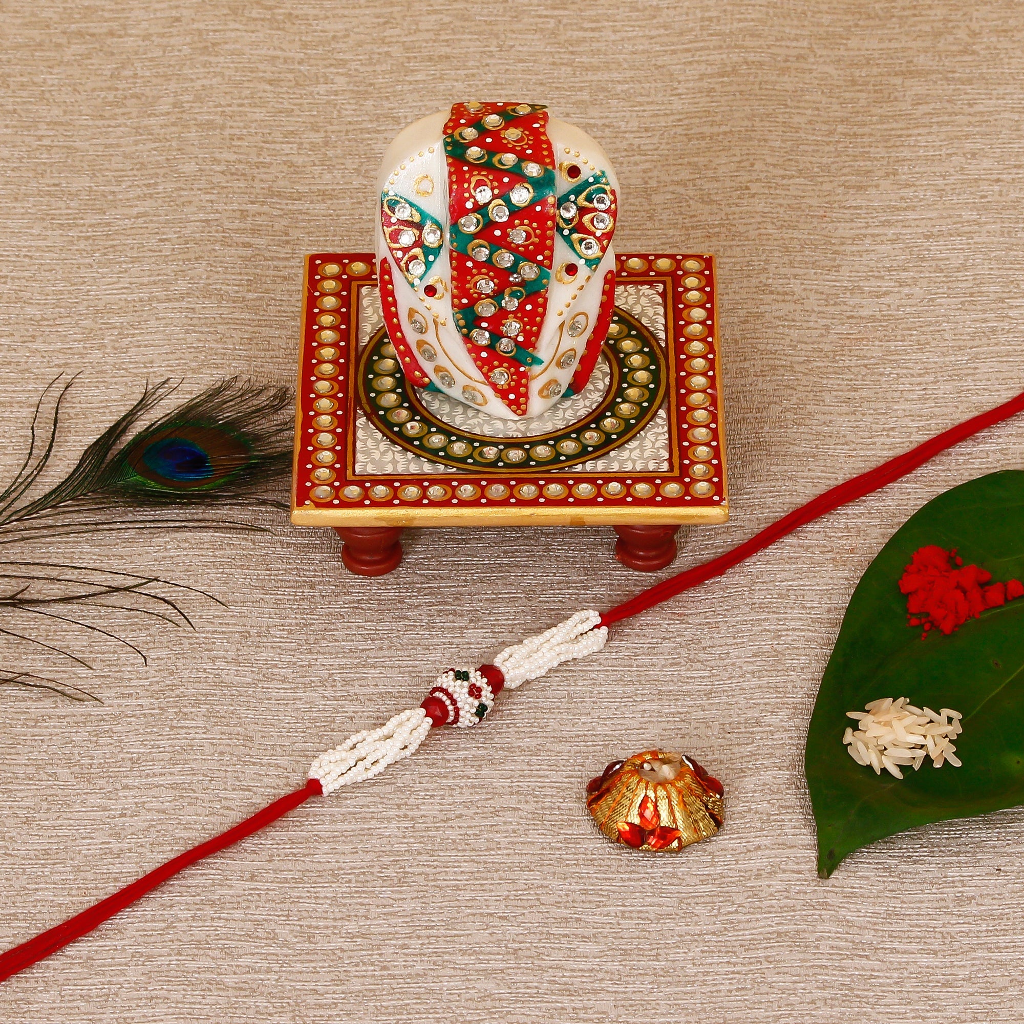Designer Pearl Rakhi with Lord Ganesha on Kundan Studded Marble Chowki and Roli Tikka Matki Kafalo