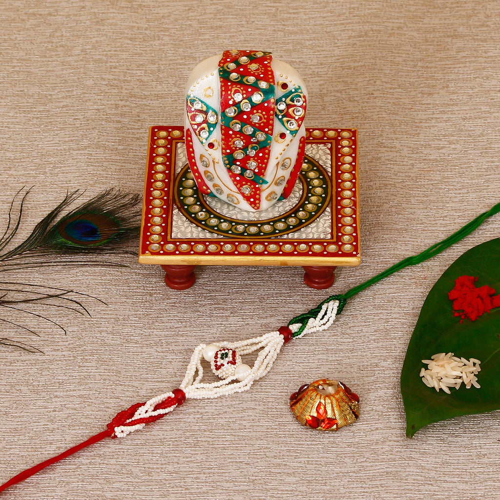 Designer Pearl Rakhi with Lord Ganesha on Kundan Studded Marble Chowki and Roli Tikka Matki Kafalo