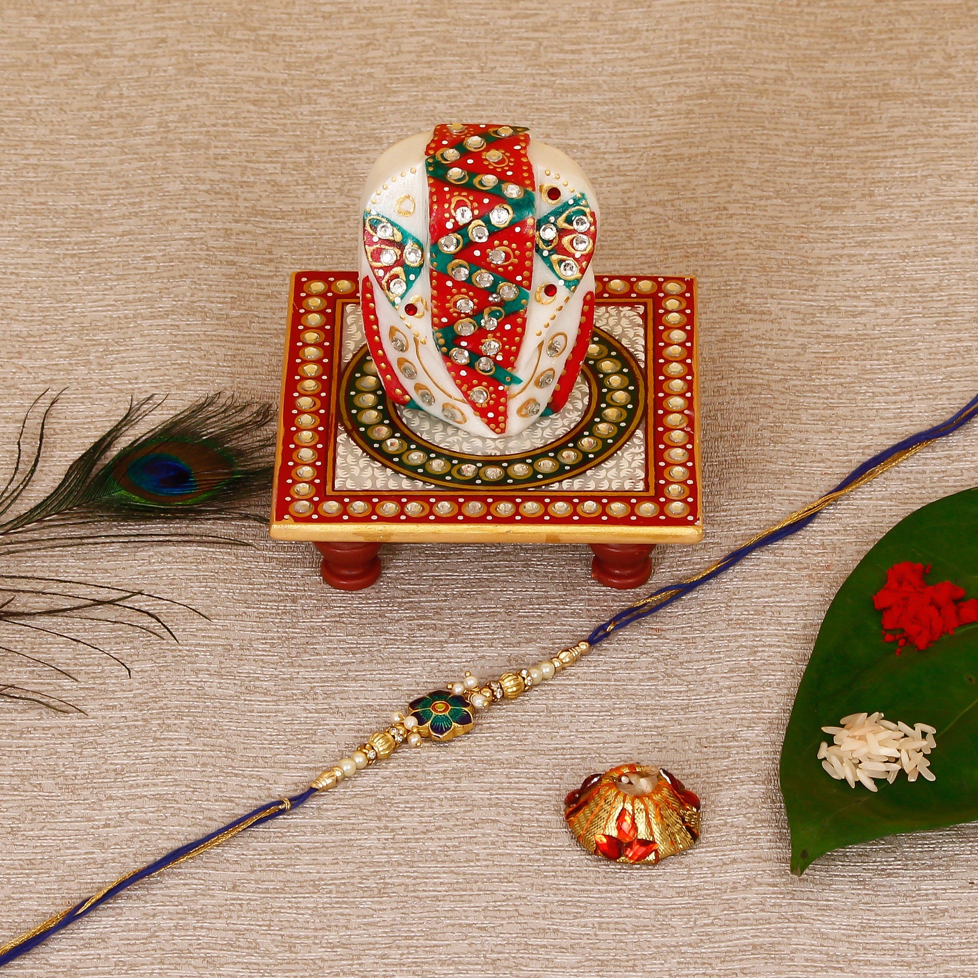 Designer Meenakari Rakhi with Lord Ganesha on Kundan Studded Marble Chowki and Roli Tikka Matki Kafalo
