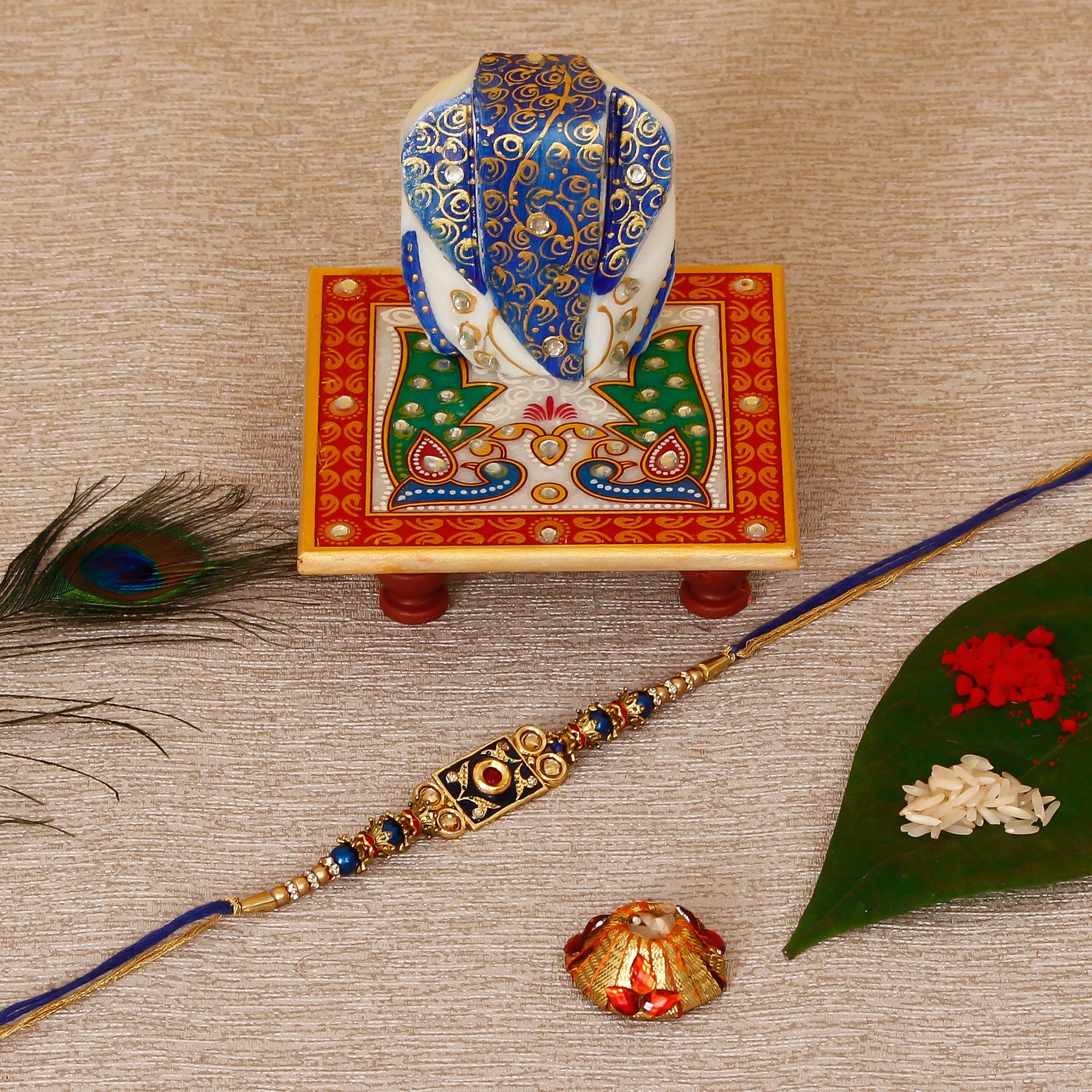 Designer Meenakari Rakhi with Lord Ganesha on Marble Chowki and Roli Tikka Matki Kafalo