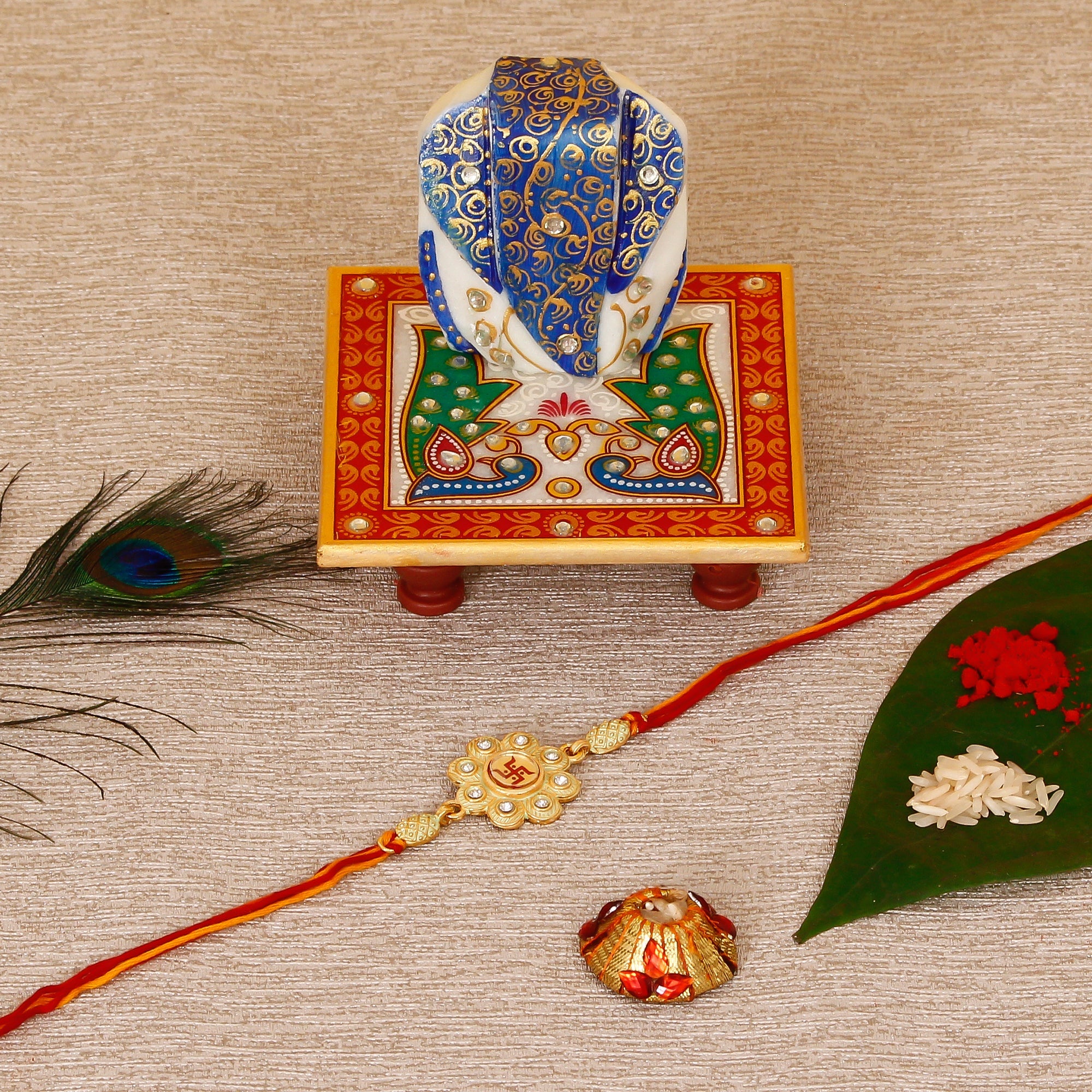 Designer Religious Swastik Rakhi with Lord Ganesha on Marble Chowki and Roli Tikka Matki Kafalo