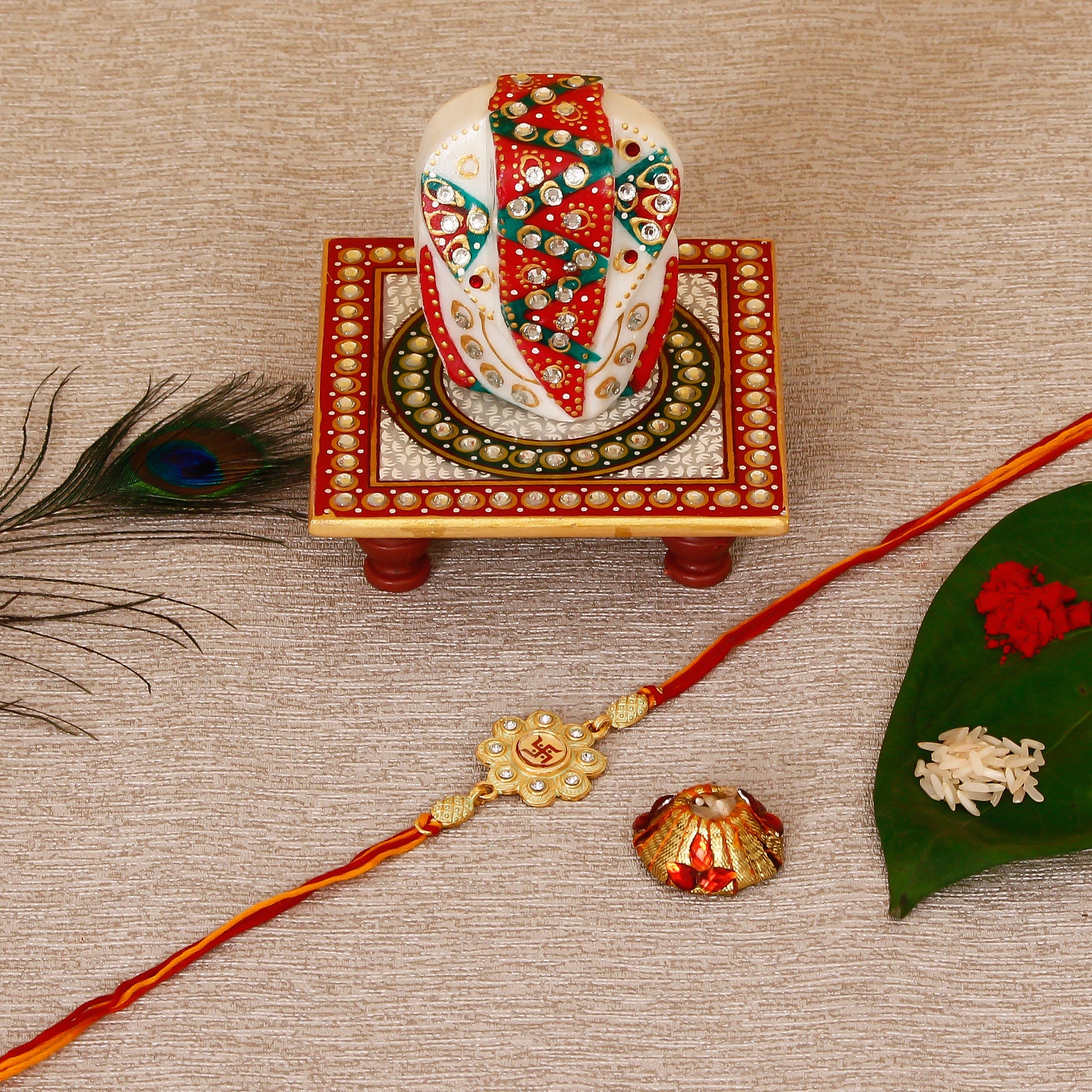 Designer Religious Swastik Rakhi with Lord Ganesha on Kundan Studded Marble Chowki and Roli Tikka Matki Kafalo