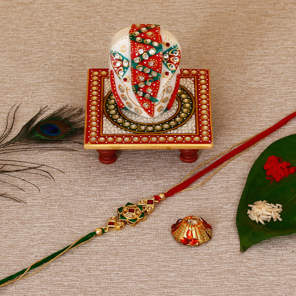 Designer Kundan Rakhi with Lord Ganesha on Kundan Studded Marble Chowki and Roli Tikka Matki Kafalo