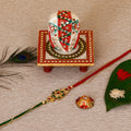 Designer Kundan Rakhi with Lord Ganesha on Kundan Studded Marble Chowki and Roli Tikka Matki Kafalo