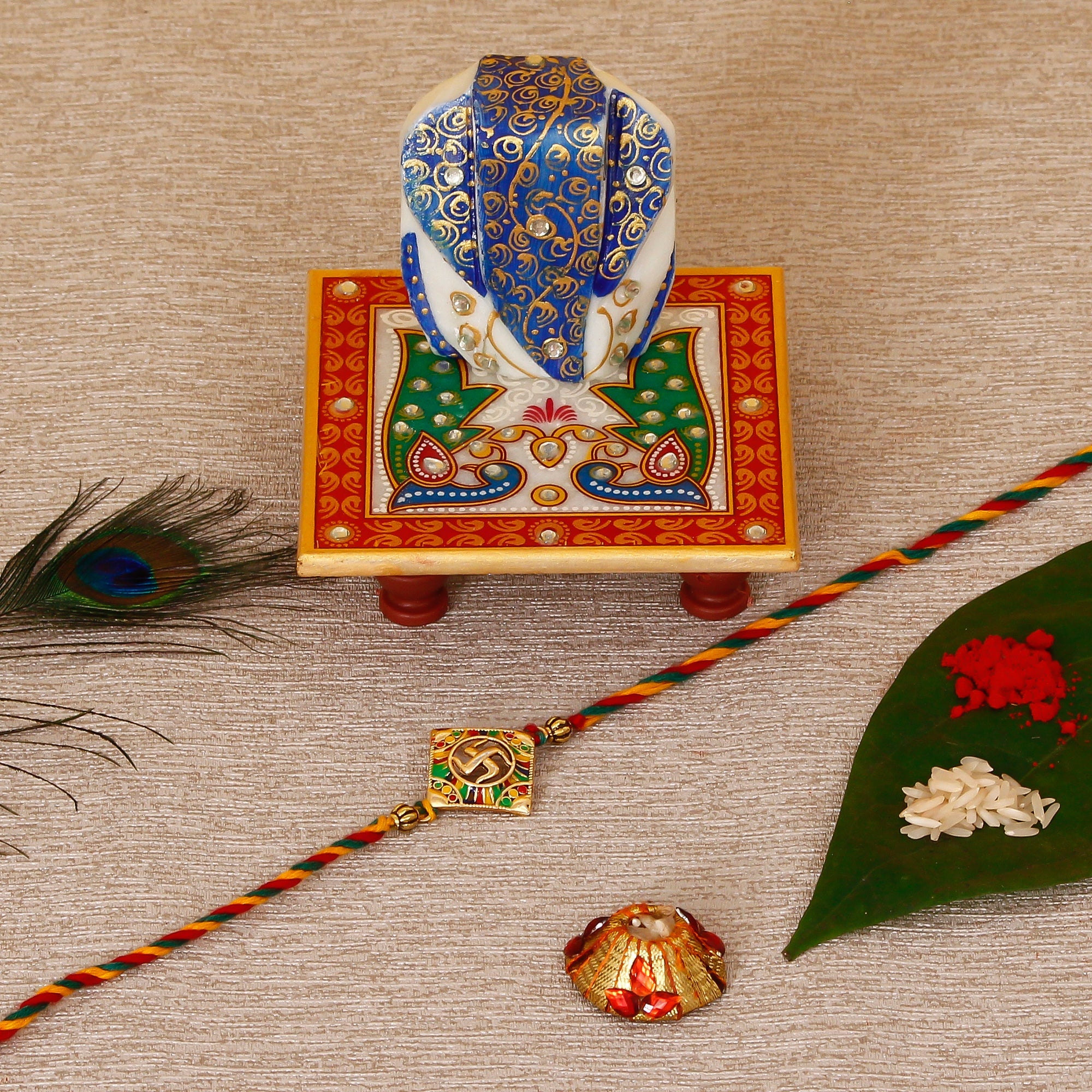 Designer Religious Swastik Rakhi with Lord Ganesha on Marble Chowki and Roli Tikka Matki Kafalo