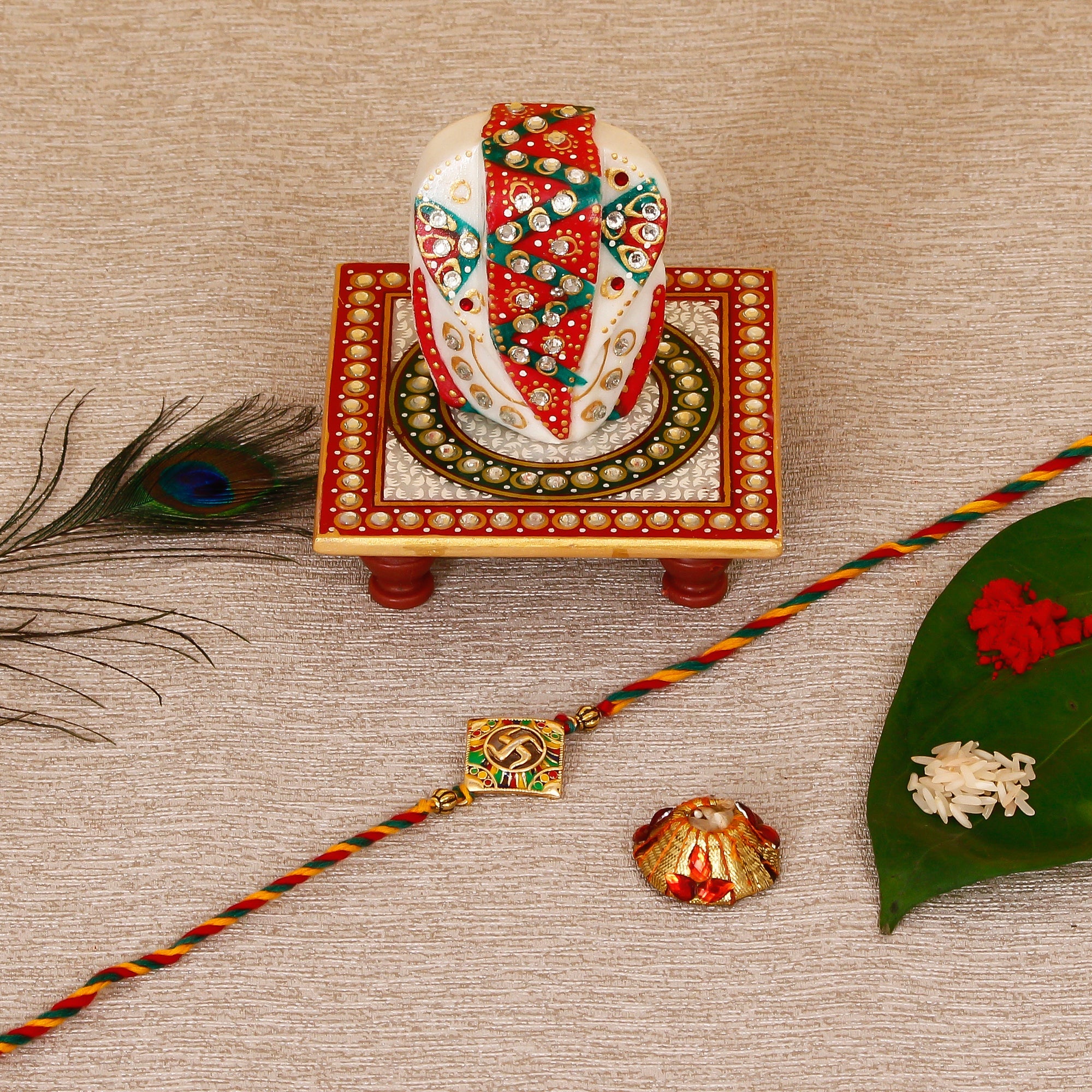 Designer Religious Swastik Rakhi with Lord Ganesha on Kundan Studded Marble Chowki and Roli Tikka Matki Kafalo