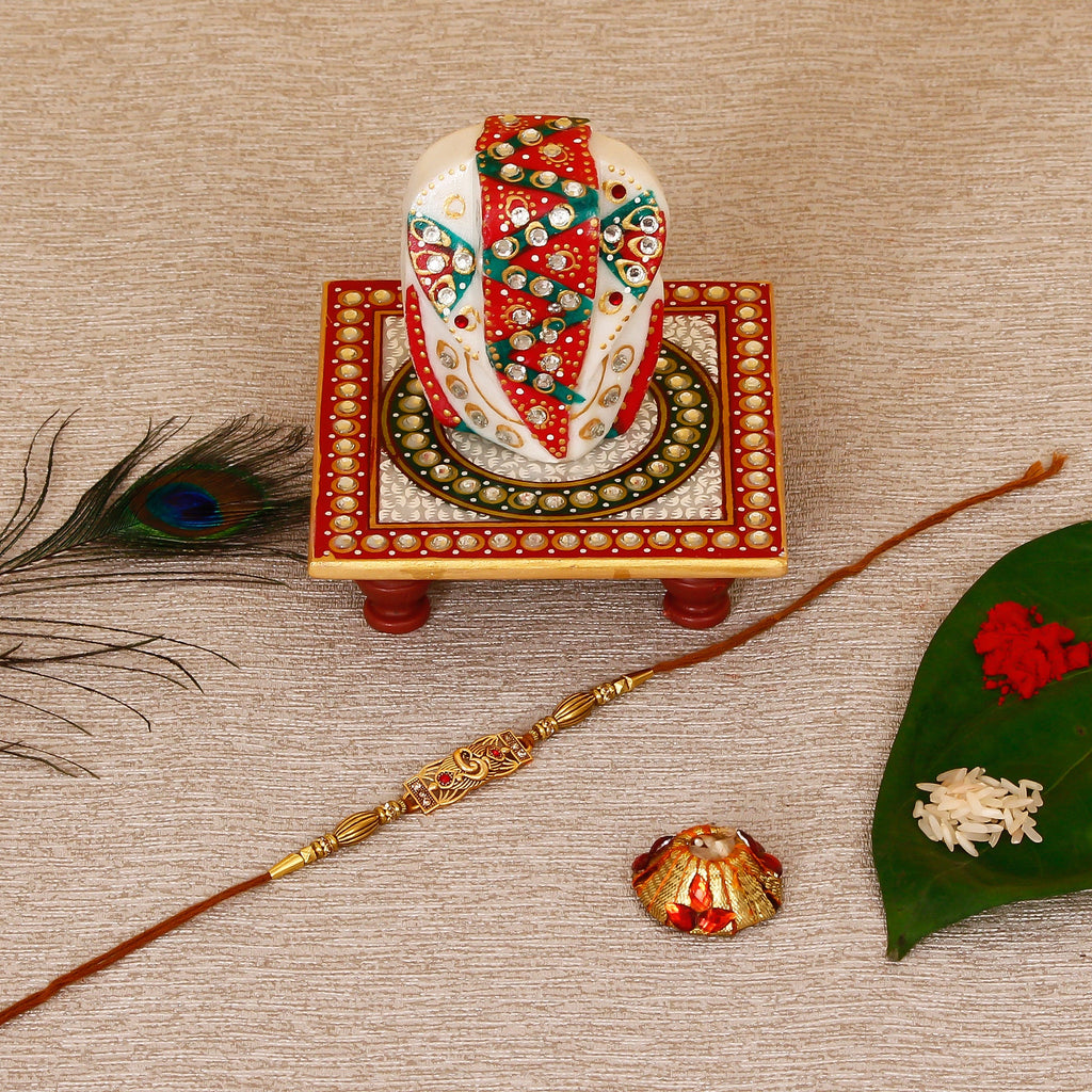 Designer Religious Rakhi with Lord Ganesha on Kundan Studded Marble Chowki and Roli Tikka Matki Kafalo