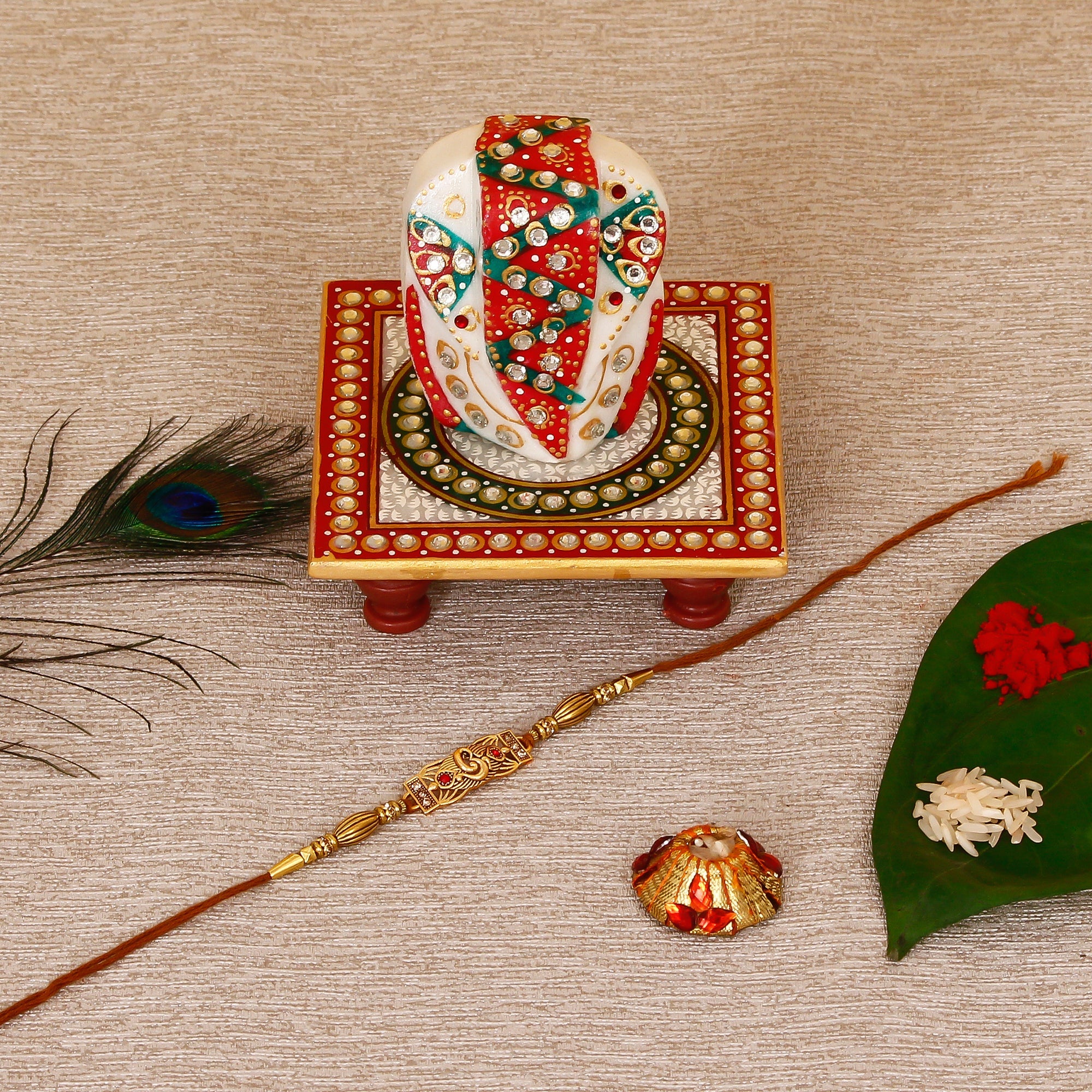 Designer Religious Rakhi with Lord Ganesha on Kundan Studded Marble Chowki and Roli Tikka Matki Kafalo