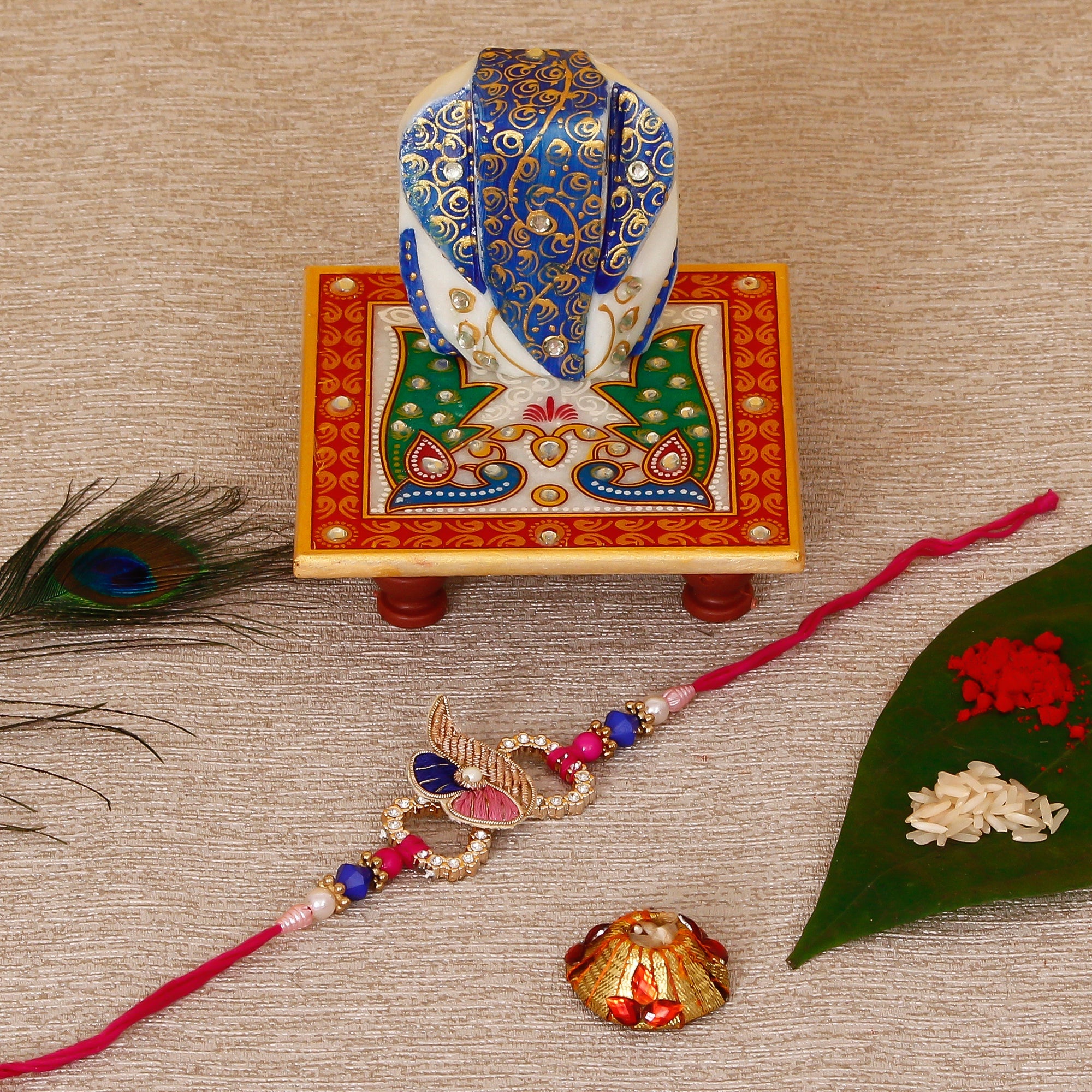 Designer Rakhi with Lord Ganesha on Marble Chowki and Roli Tikka Matki Kafalo