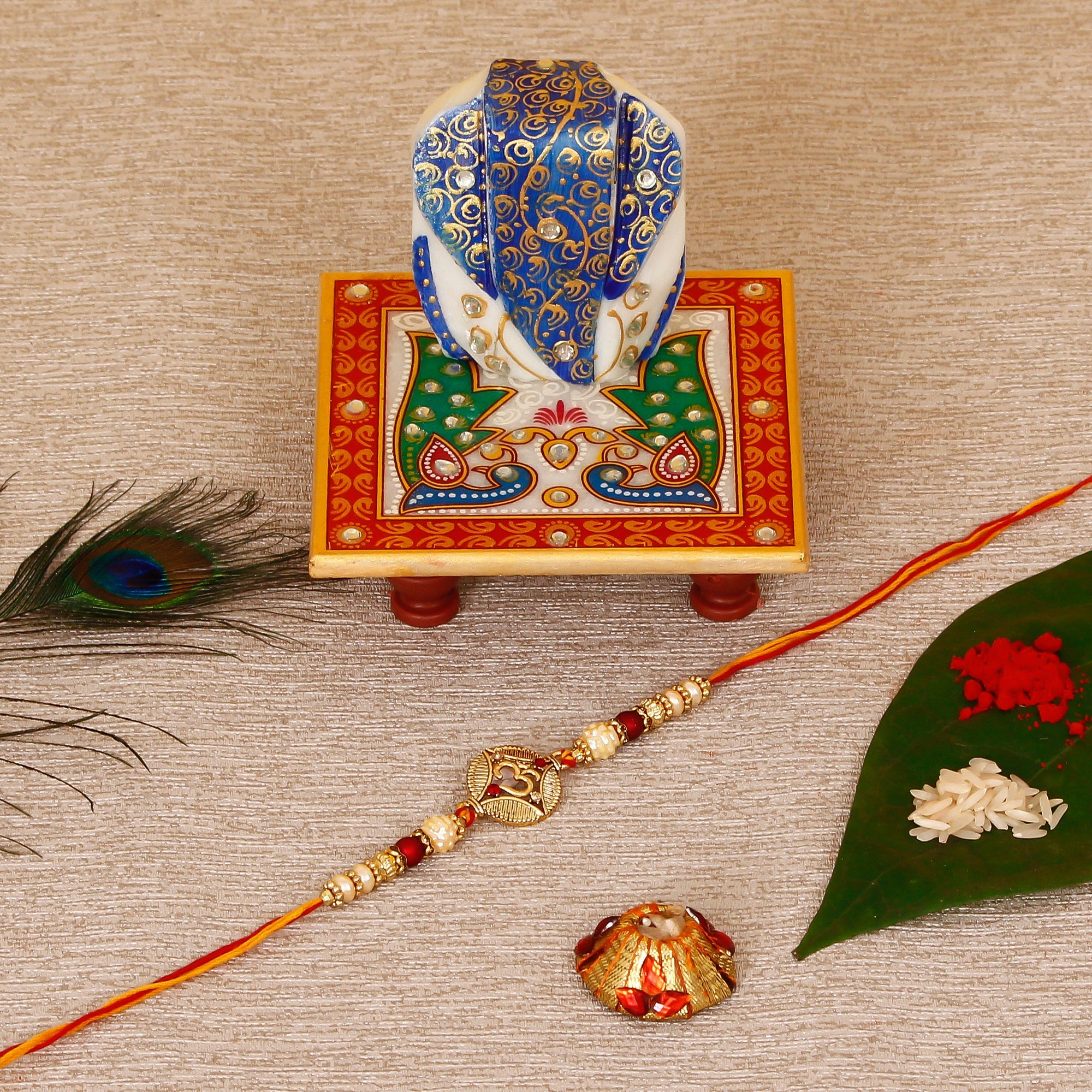 Designer OM Rakhi with Lord Ganesha on Marble Chowki and Roli Tikka Matki Kafalo