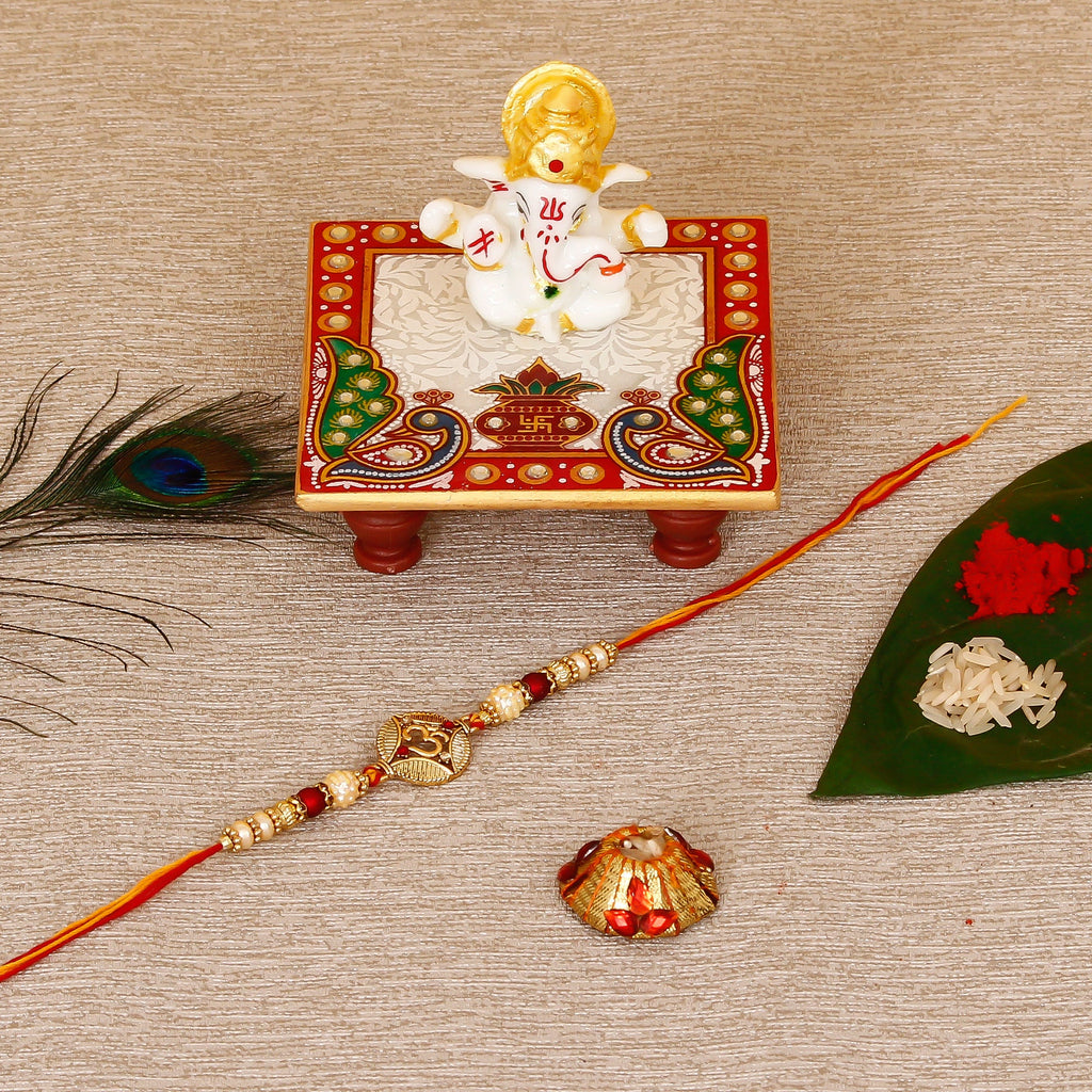 Designer OM Rakhi with Lord Ganesha Marble Chowki and Roli Tikka Matki Kafalo