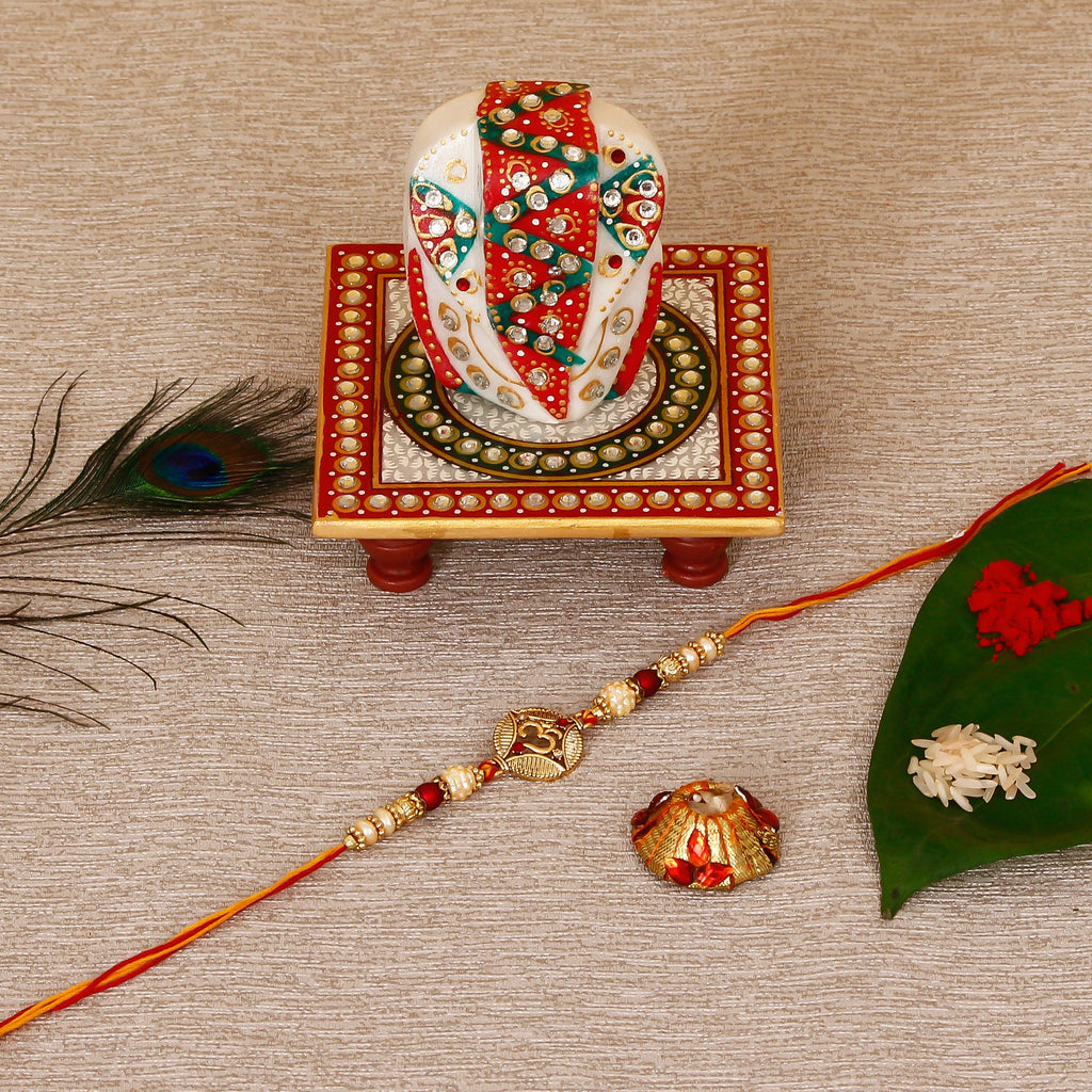 Designer OM Rakhi with Lord Ganesha on Kundan Studded Marble Chowki and Roli Tikka Matki Kafalo