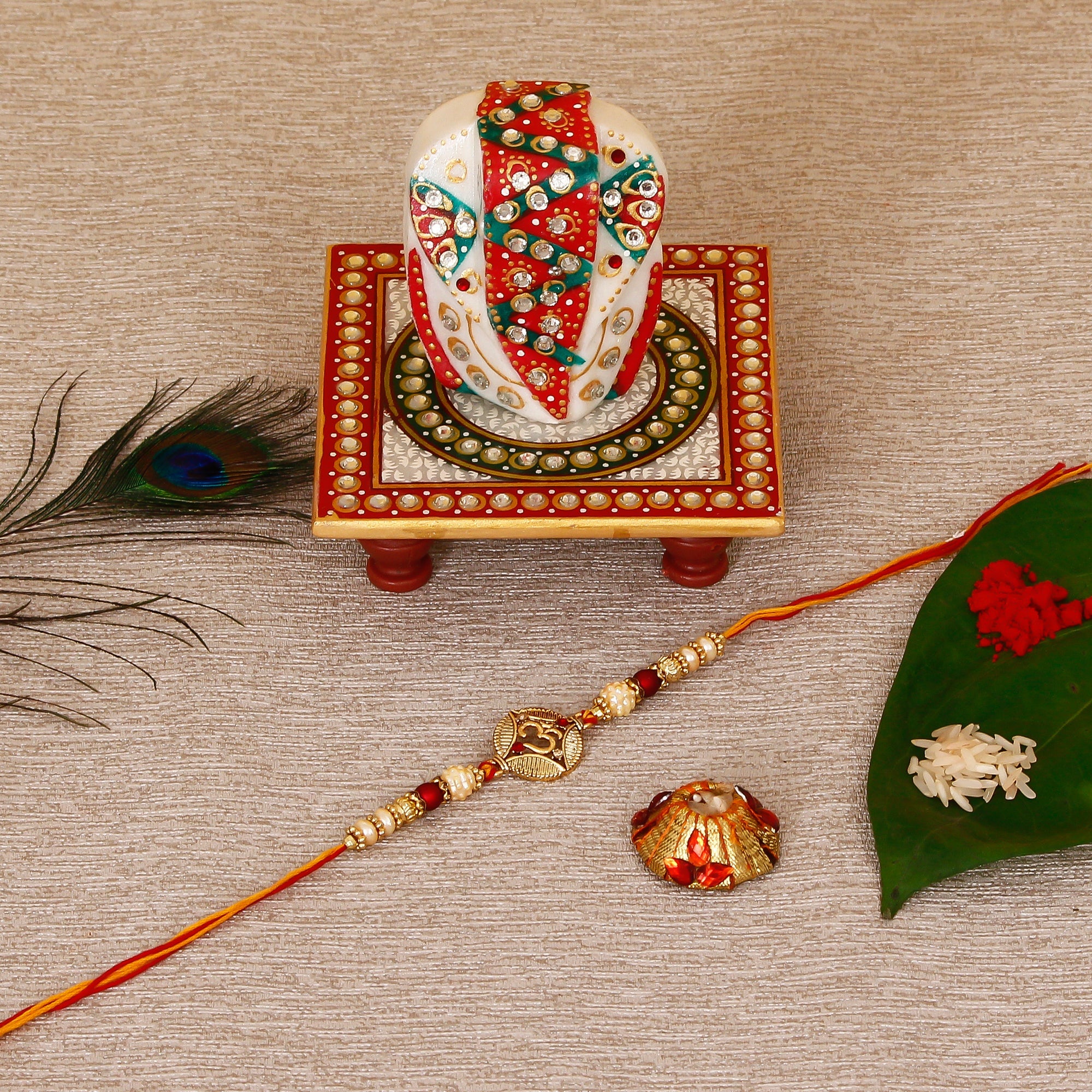 Designer OM Rakhi with Lord Ganesha on Kundan Studded Marble Chowki and Roli Tikka Matki Kafalo
