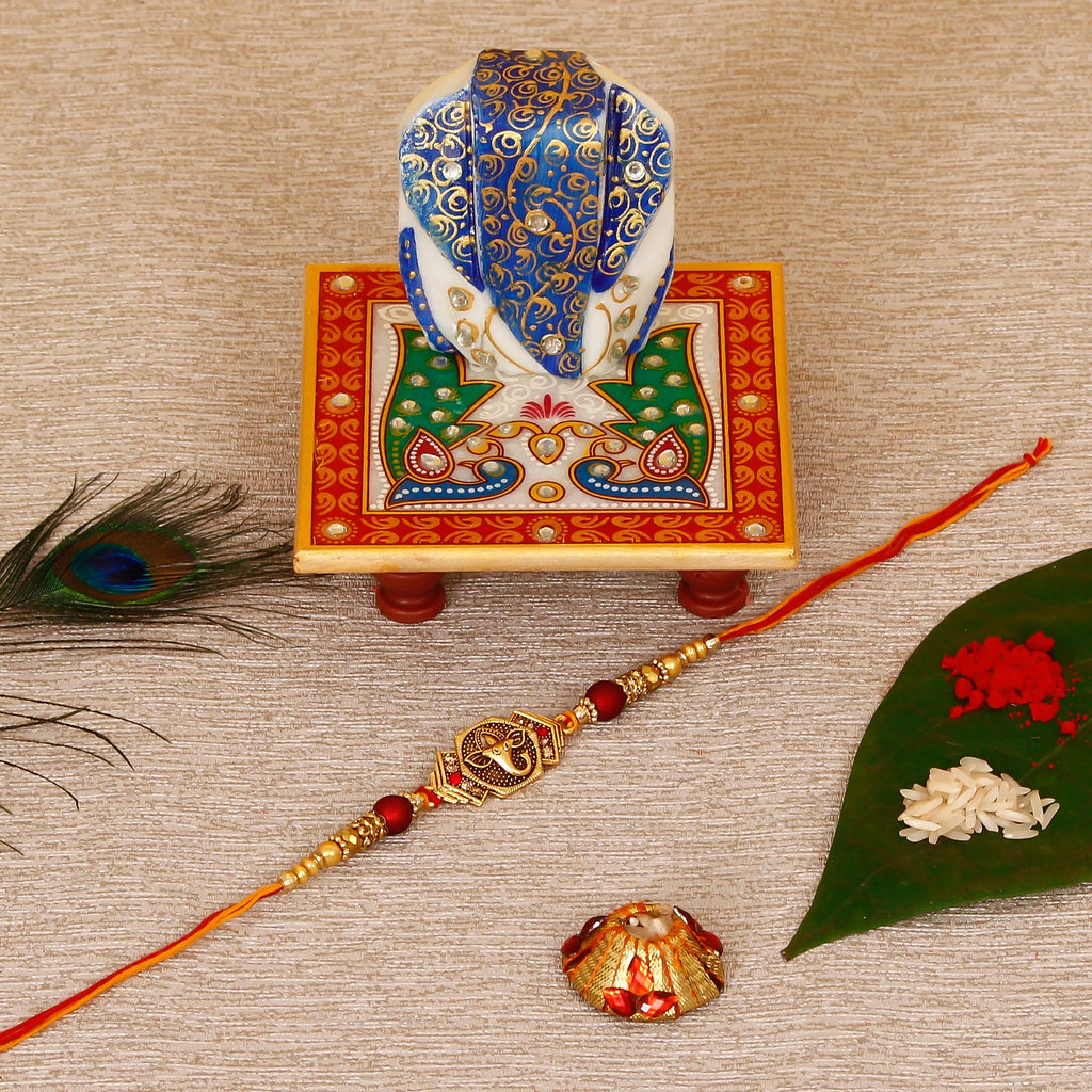 Designer Religious Ganesha Rakhi with Lord Ganesha on Marble Chowki and Roli Tikka Matki Kafalo