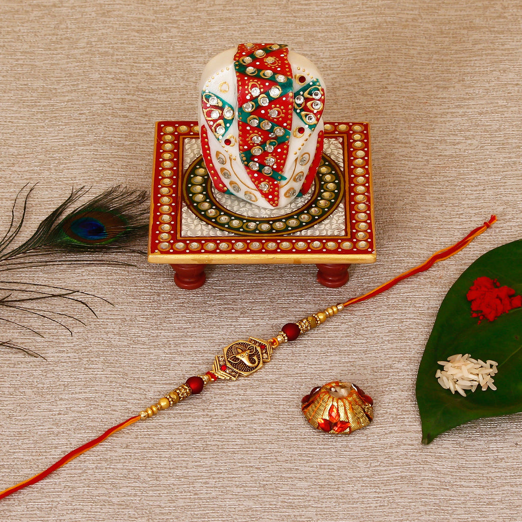 Designer Religious Ganesha Rakhi with Lord Ganesha on Kundan Studded Marble Chowki and Roli Tikka Matki Kafalo