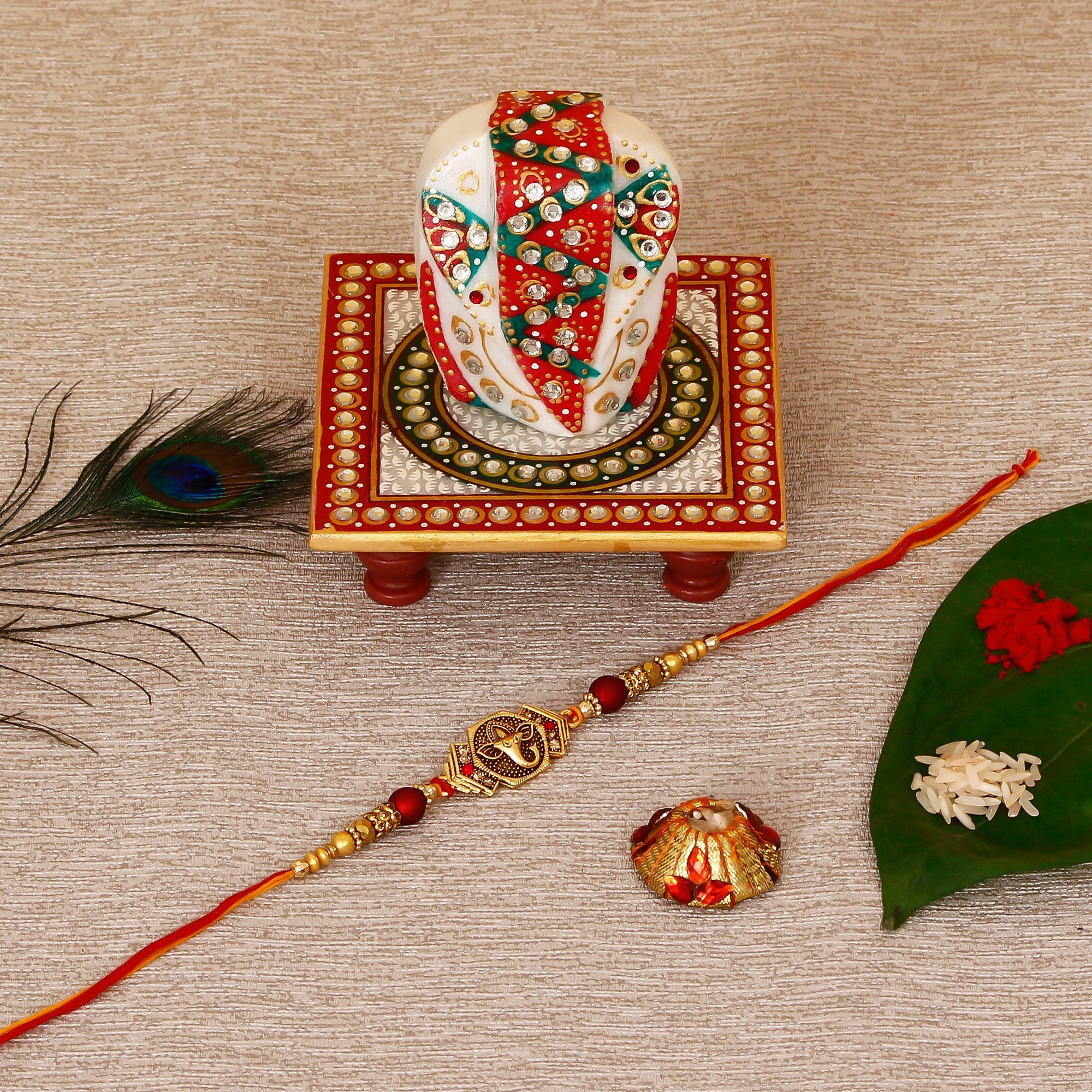 Designer Religious Ganesha Rakhi with Lord Ganesha on Kundan Studded Marble Chowki and Roli Tikka Matki Kafalo