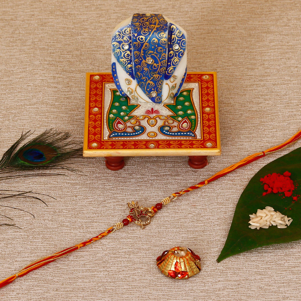 Designer Religious OM Rakhi with Lord Ganesha on Marble Chowki and Roli Tikka Matki Kafalo