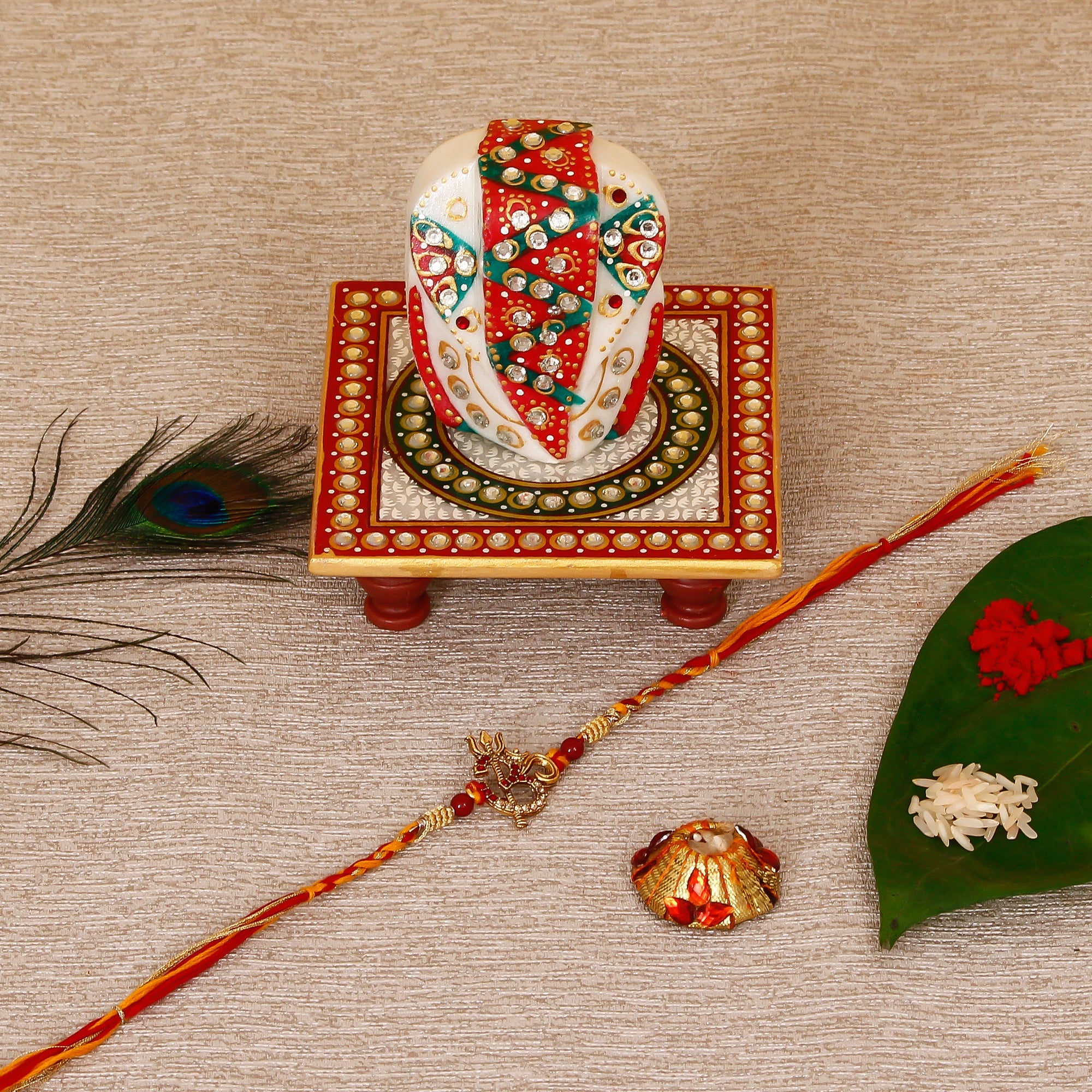 Designer Religious OM Rakhi with Lord Ganesha on Kundan Studded Marble Chowki and Roli Tikka Matki Kafalo