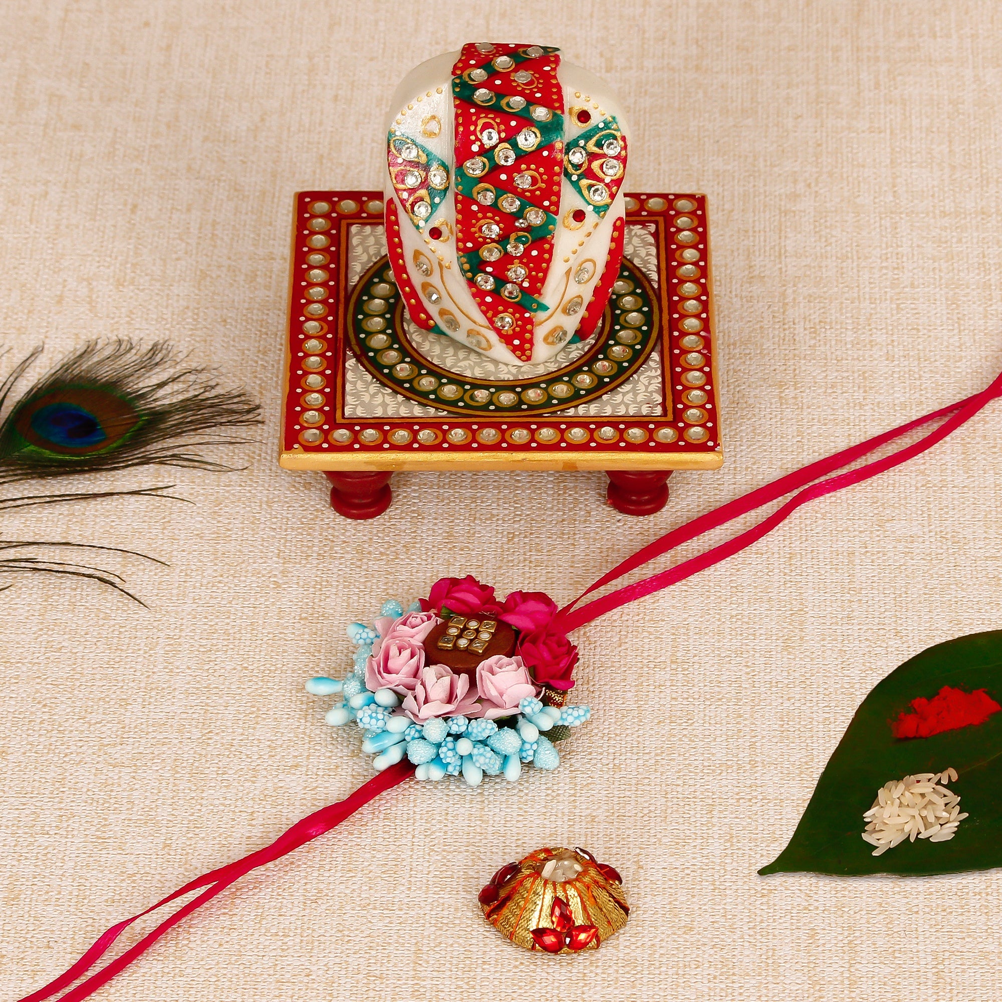 Designer Floral Rakhi with Lord Ganesha on Kundan Studded Marble Chowki and Roli Tikka Matki Kafalo