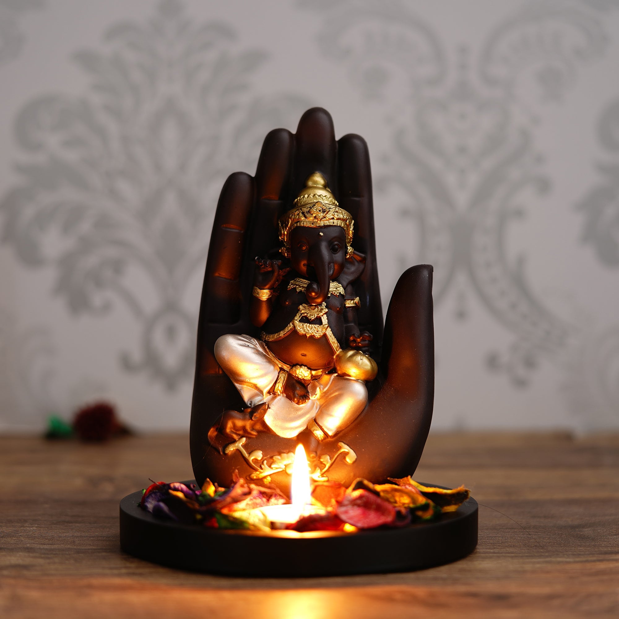 Golden and Black Handcrafted Palm Ganesha Idol on Wooden Base with Fragranced Petals Tealight Candle Holder Kafalo