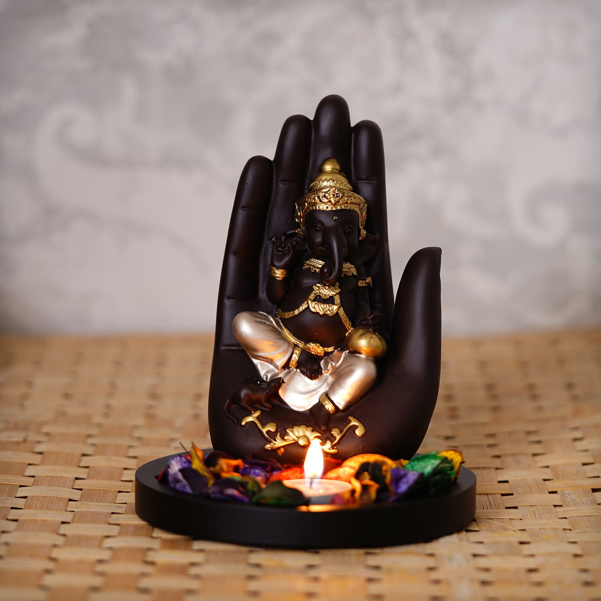 Golden and Black Handcrafted Palm Ganesha Idol on Wooden Base with Fragranced Petals Tealight Candle Holder Kafalo