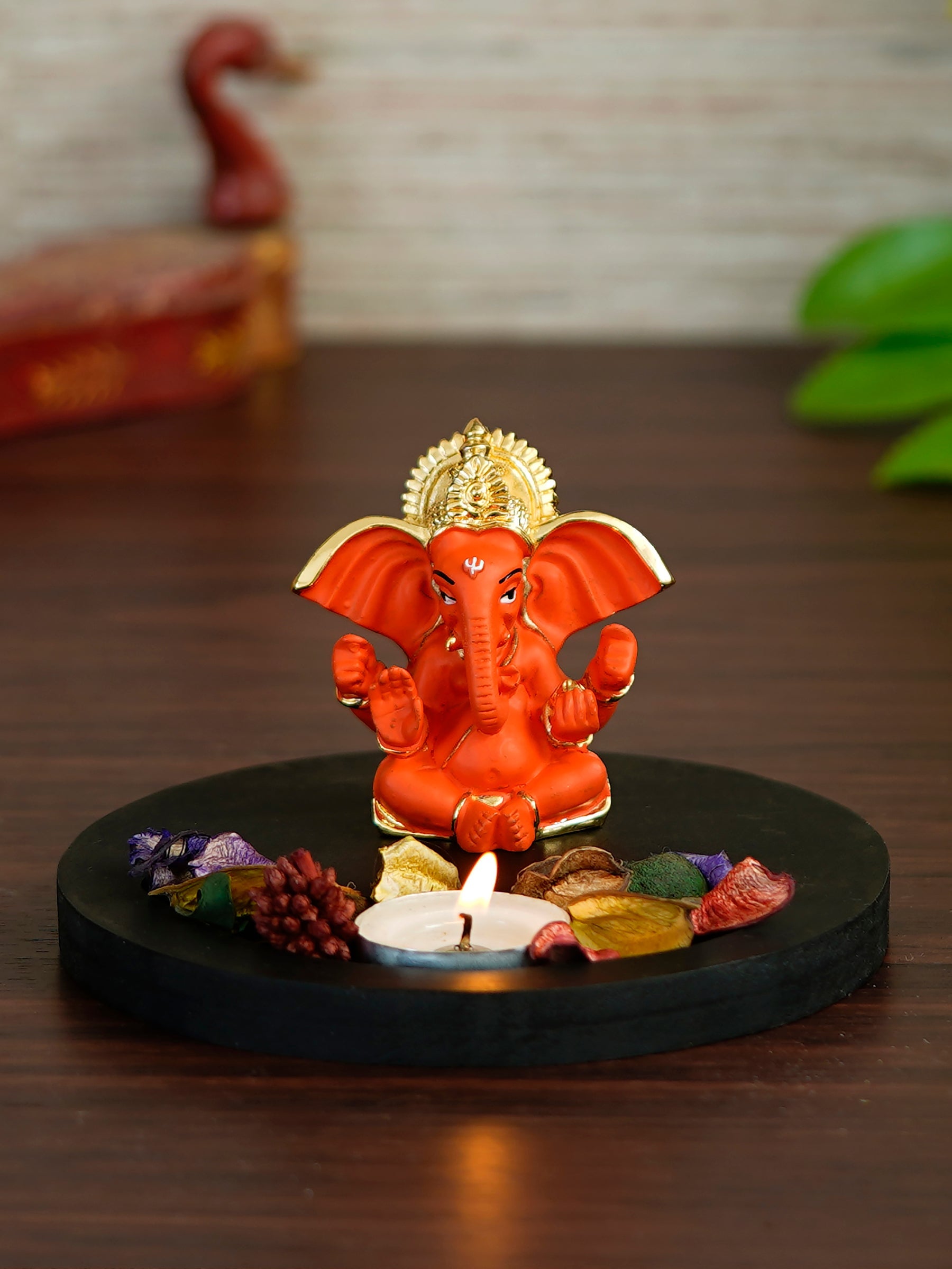 Gold Plated Orange Ganesha Idol with Wooden Base, Fragranced Petals and Tealight Kafalo