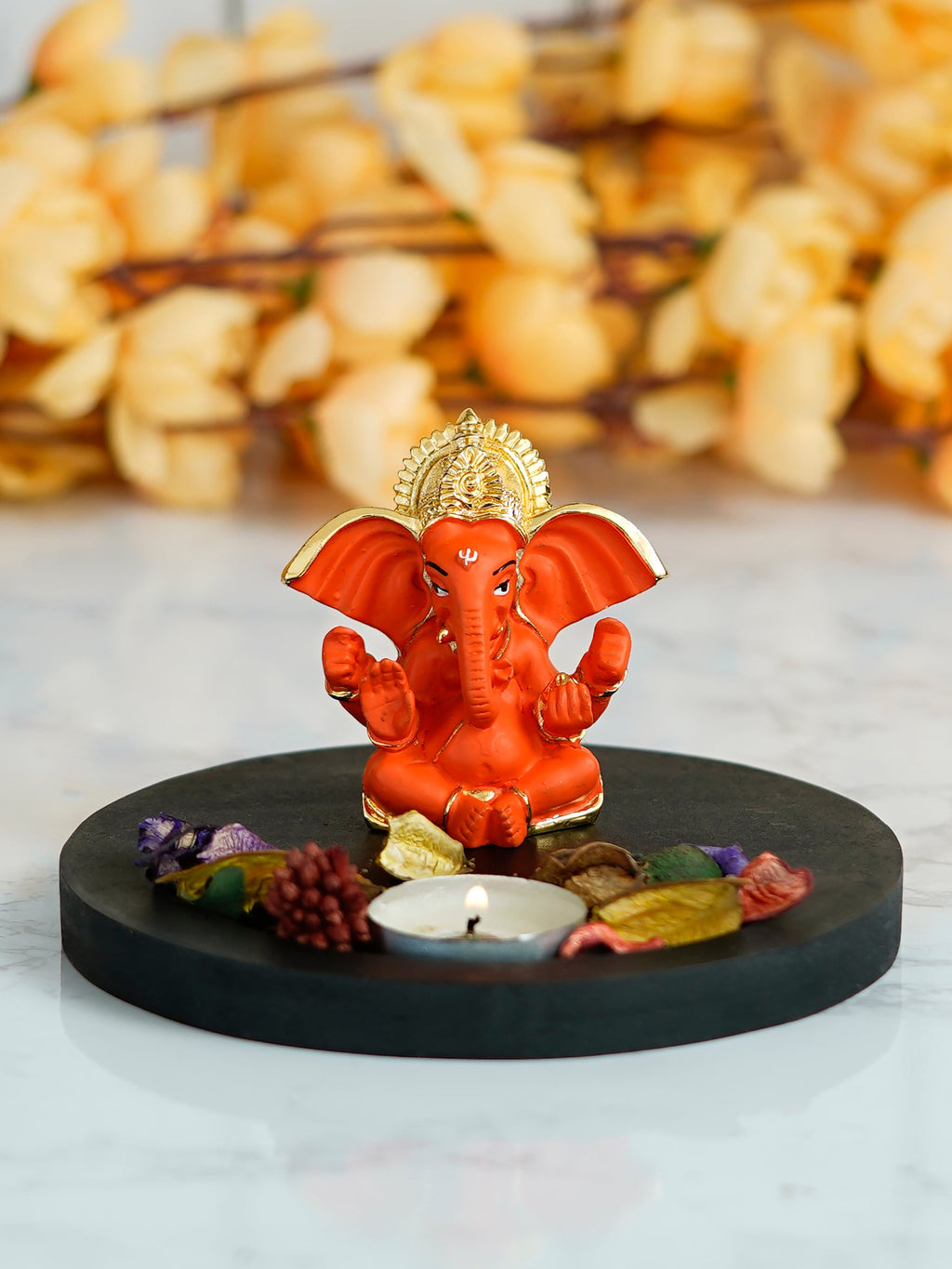 Gold Plated Orange Ganesha Idol with Wooden Base, Fragranced Petals and Tealight Kafalo